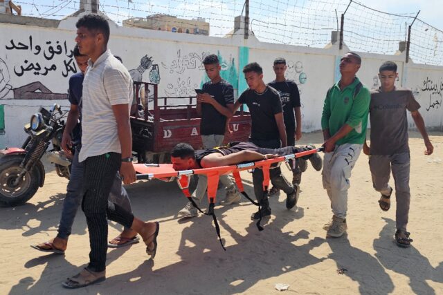 Palestinians carry a man towards a hospital in Rafah after he was wounded while queuing fo