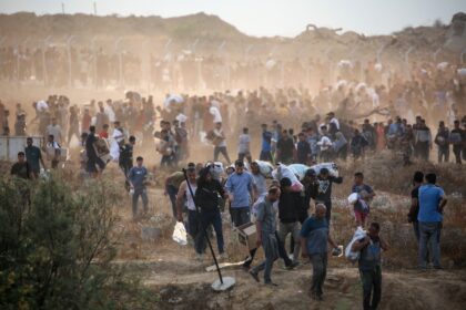 Palestinians carry supplies from a Gaza Humanitarian Foundation aid point in the central G