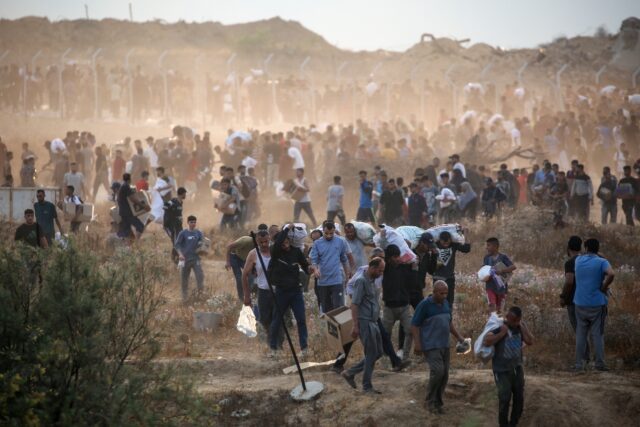 Palestinians carry supplies from a Gaza Humanitarian Foundation aid point in the central G