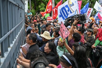 People bang on the gates of the Philippine Senate on Wednesday as they protest its decisio