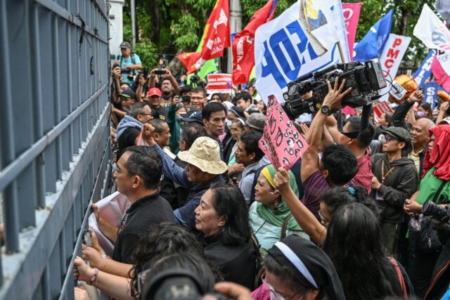 People bang on the gates of the Philippine Senate on Wednesday as they protest its decisio