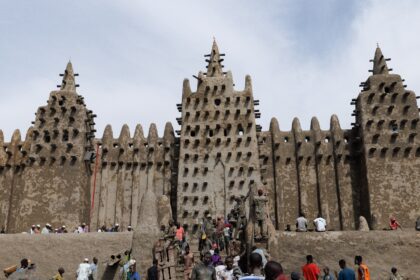 Residents apply traditional mud plaster to the Great Mosque of Djenne during the annual re