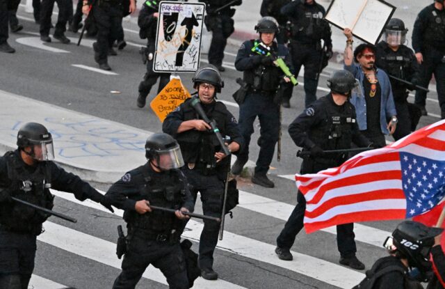 Riot police clear protesters in Los Angeles ahead of a nighttime curfew