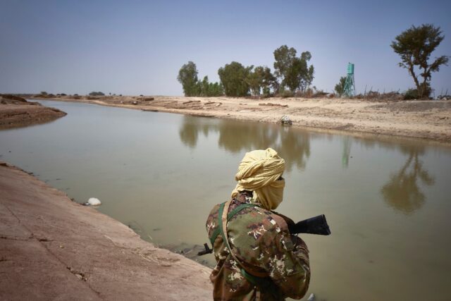 A soldier on patrol along a riverbank in Mali