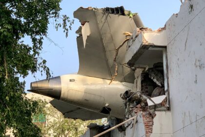 The tailpiece of the crashed Air India Dreamliner juts from a building in Ahmedabad