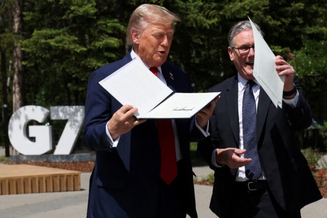 US President Donald Trump holds a signed US-UK trade deal next to British Prime Minister K