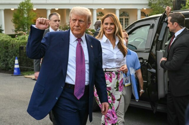 US President Donald Trump (L) raises a fist next to US First Lady Melania Trump during the