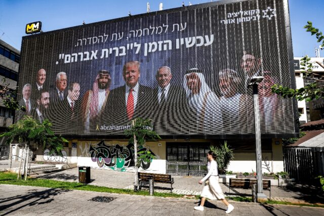 A woman walks past a billboard in Tel Aviv that promotes peace with leaders of the region
