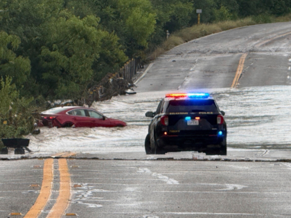 A police vehicle blocks a flooded roadway in San Antonio, Tx., where a vehicle was strande