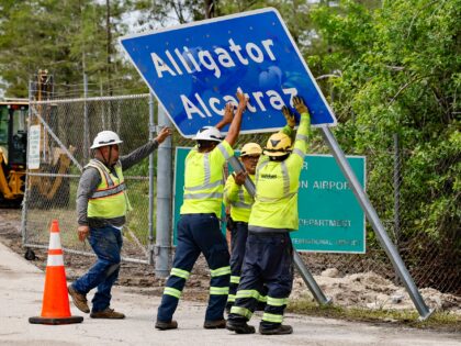 Workers install a permanent Alligator Alcatraz sign. The facility is within the Florida Ev
