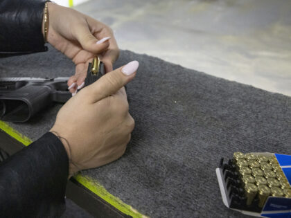 A participant loads a magazine with bullets during a training session at a shooting range