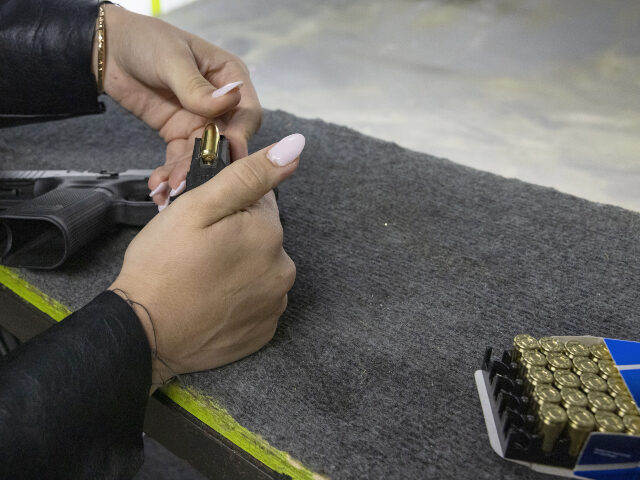 A participant loads a magazine with bullets during a training session at a shooting range