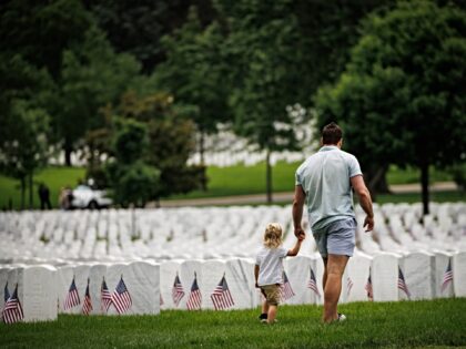 ARLINGTON, VIRGINIA - MAY 26: A father and son walk past the headstones of fallen service