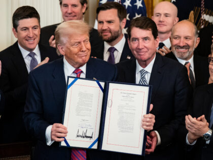 President Donald Trump displays the signed bill during a signing ceremony for the GENIUS A