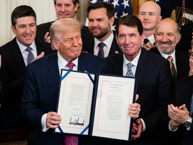 President Donald Trump displays the signed bill during a signing ceremony for the GENIUS A