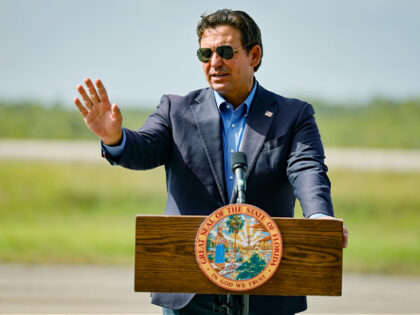 Governor Ron DeSantis speaks to reporters during a press conference as he stands on the ai