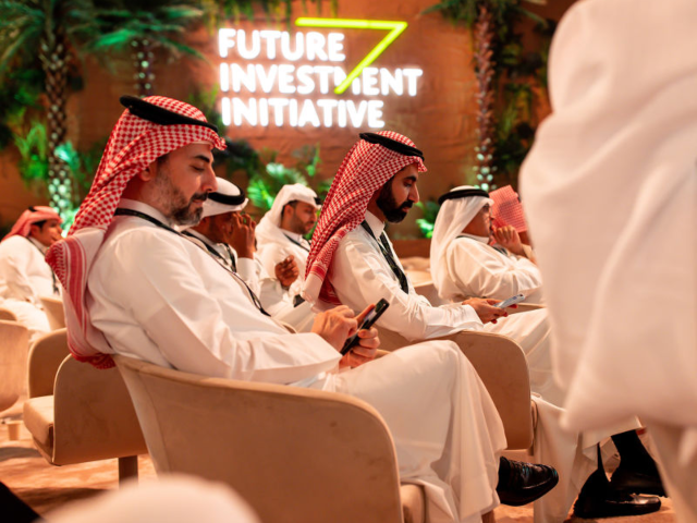 Attendees browse smartphones in the audience on day two of the Future Investment Initiativ