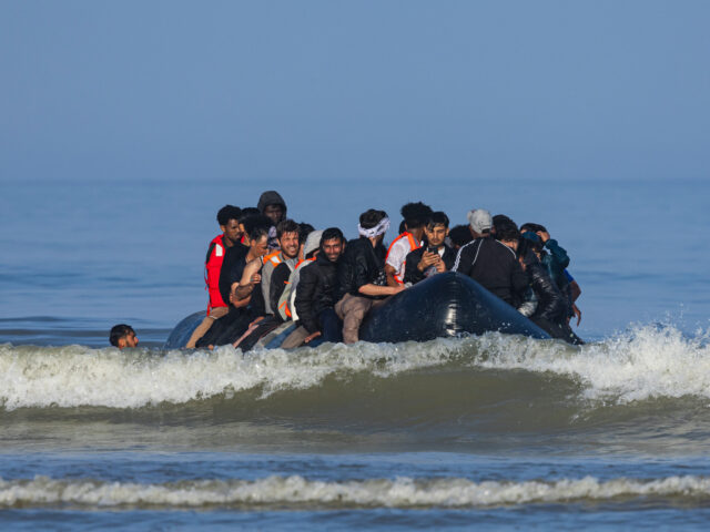 Migrants board a smuggler's boat in an attempt to cross the English Channel off the beach