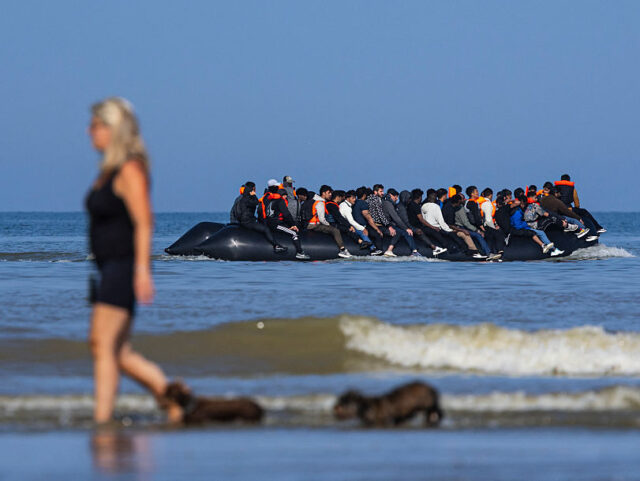 TOPSHOT-FRANCE-BRITAIN-EU-MIGRANTS TOPSHOT - A tourist walks her dogs as migrants board a smuggler's boat in an attempt