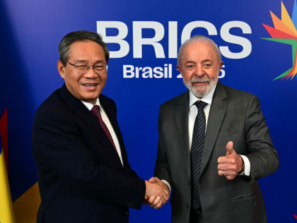 Brazil's President Luiz Inacio Lula da Silva (R) gives his thumb up while shaking hands wi