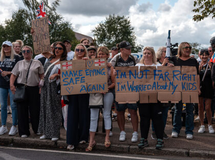 EPPING, ENGLAND - JULY 20: Protesters hold placards as they gather outside the Bell Hotel