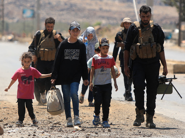 GettyImages-2225418938 A Syrian family is escorted by government security out of the city of Sweida, on July 21,