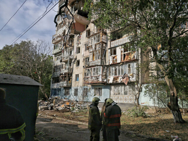 Firefighters stand outside an apartment block damaged by a Russian drone attack in Odesa,