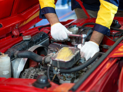 Closeup mechanic hand in work uniform, working on a car in an automotive shop or garage. H