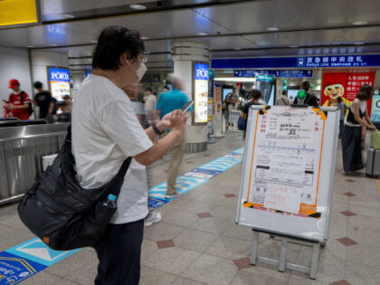 A man checks a notice indicating that some trains are suspended due to a tsunami warning a