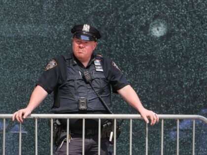 A New York City Police (NYPD) officer stands outside the 345 Park Avenue building, the sce
