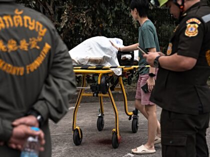 A relative touches the body of a shooting victim on a stretcher at Or Tor Kor market in Ba