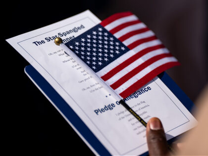 An attendee holds the US flag and the lyrics of the Star Spangled Banner during a naturali