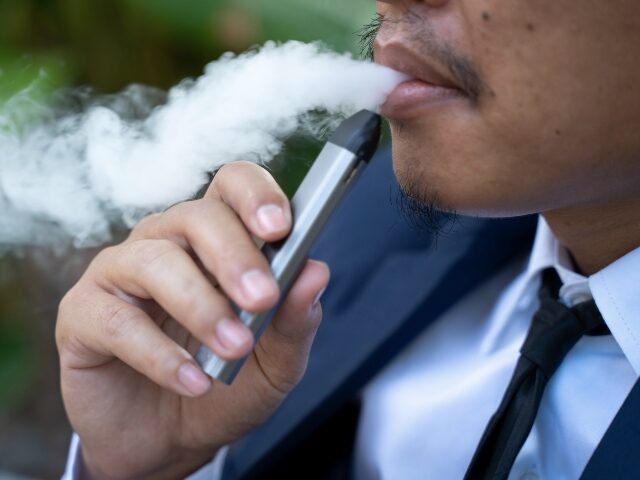 Young male worker smoking electronic cigarette