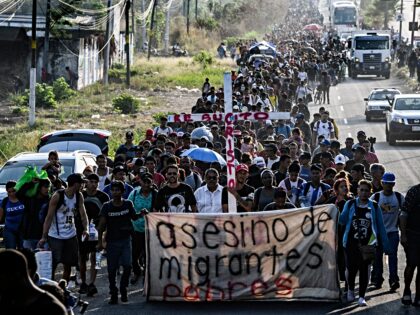 A group of migrants of different nationalities carry a cross leading a caravan that aims t