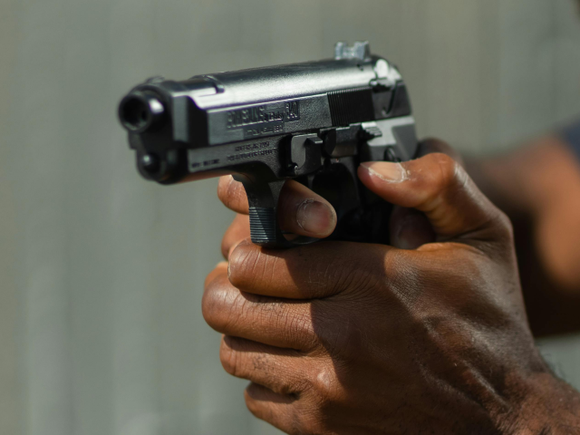 Man in Gray Police Uniform Holding a Gun