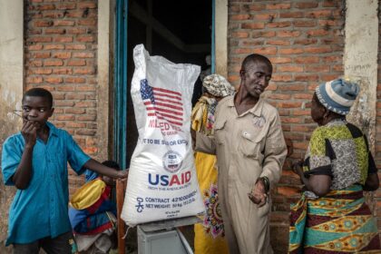 A Burundian government official speaks with newly arrived Congolese refugees while weighin
