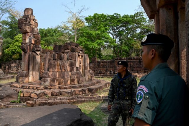 A Cambodian soldier (R) and Thai soldier stand guard at a disputed ancient Khmer temple on