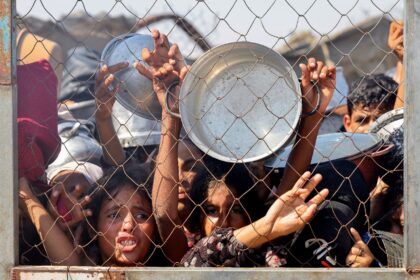 Palestinians, mostly children, push to receive a hot meal at a charity kitchen in the Mawa