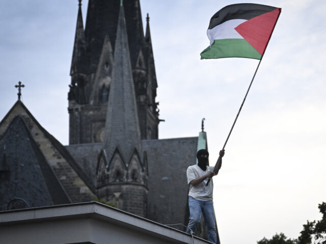 BERLIN, GERMANY - OCTOBER 07: A man with a mask on his face waves a Palestinian flag on th