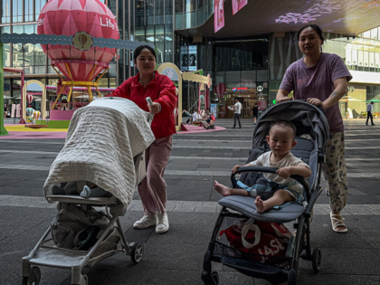CHONGQING, CHINA - MAY 20: Women push strollers with young children through a commercial p