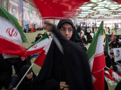 Veiled Iranian mourners wave the country's flags while participating in a memorial ceremon