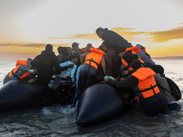 Migrants try to to board a smuggler's inflatable dinghy in an attempt to cross the English