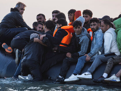 Migrants try to board a smuggler's inflatable dinghy in an attempt to cross the Engli