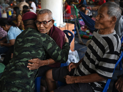A Thai soldier is hugged by an evacuee as military attaches and diplomats from 23 foreign