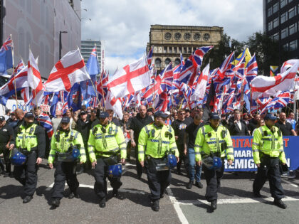 Police walk ahead of far-right Britain First party supporters waving Union Flags and St Ge