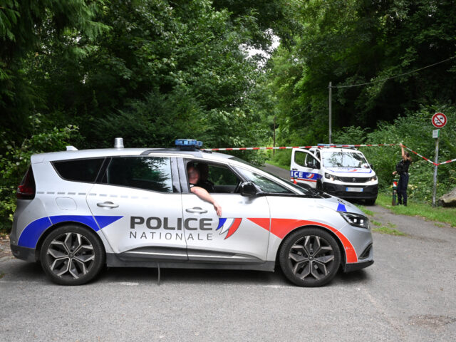 Police cars are parked in front of a cordoned-off area, near a sports field where a 32-yea