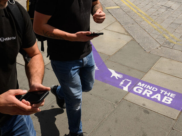 Currys Launches 'Mind the Grab' Campaign On Oxford Street To Raise Awareness Over Mobile Phone Theft LONDON, ENGLAND - AUGUST 06: Pedestrians walk over newly-installed signage warning people