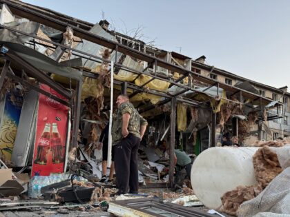 ZAPORIZHZHIA, UKRAINE - AUGUST 30: People clean up debris at destroyed bus stop and store