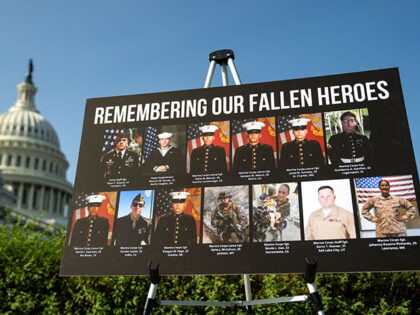 A sign displaying photos and names of the 13 service members killed in a terrorist attack