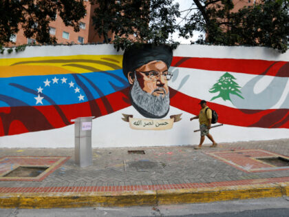 A man walks by a mural painted by the "Somos Venezuela" Movement depicting the L